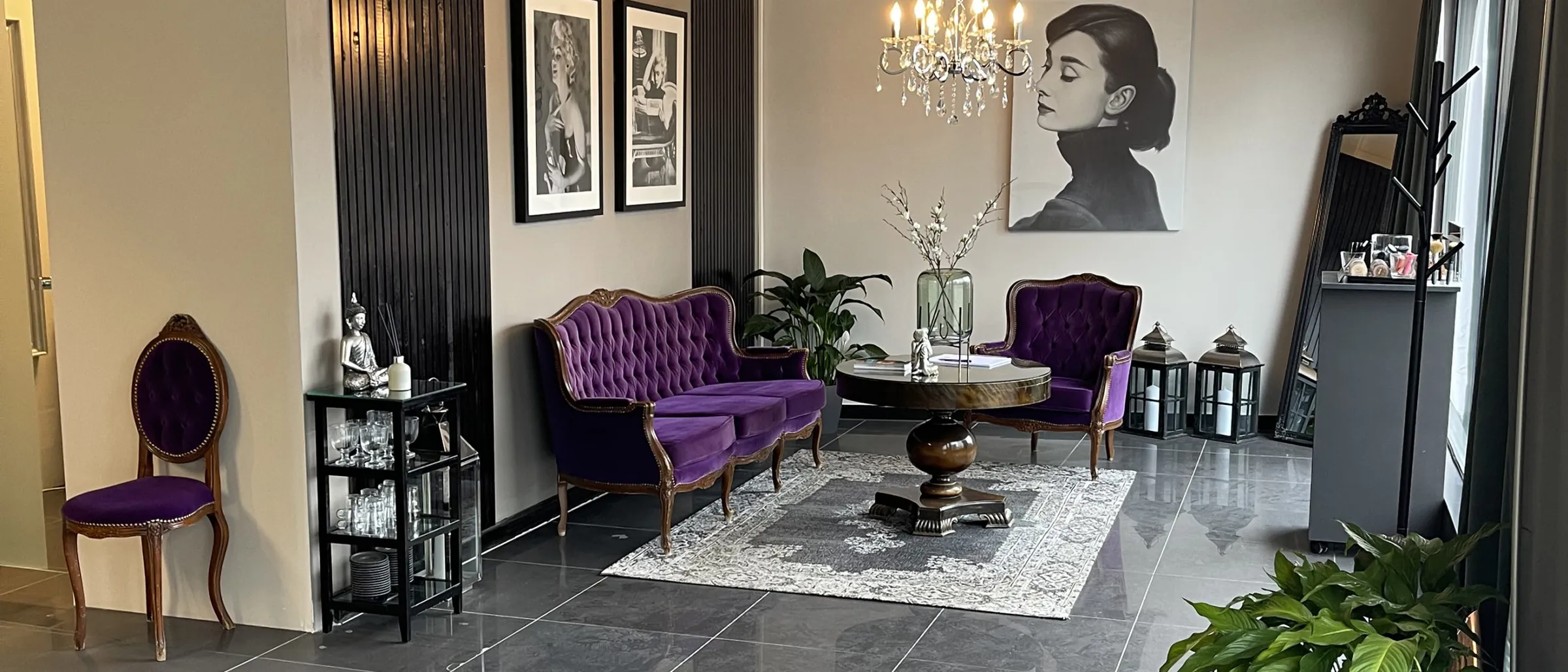 Loungen hos Clinique Marine med fl&oslash;yelssofa, lysekrone og portrett p&aring; veggen
